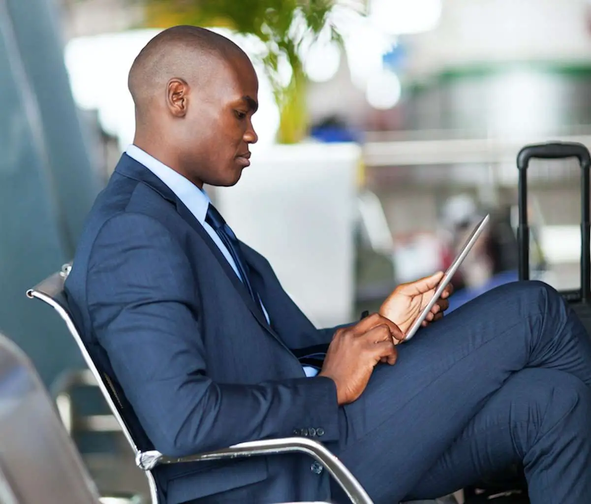Black man businessman playing with his tablet about to board a plane