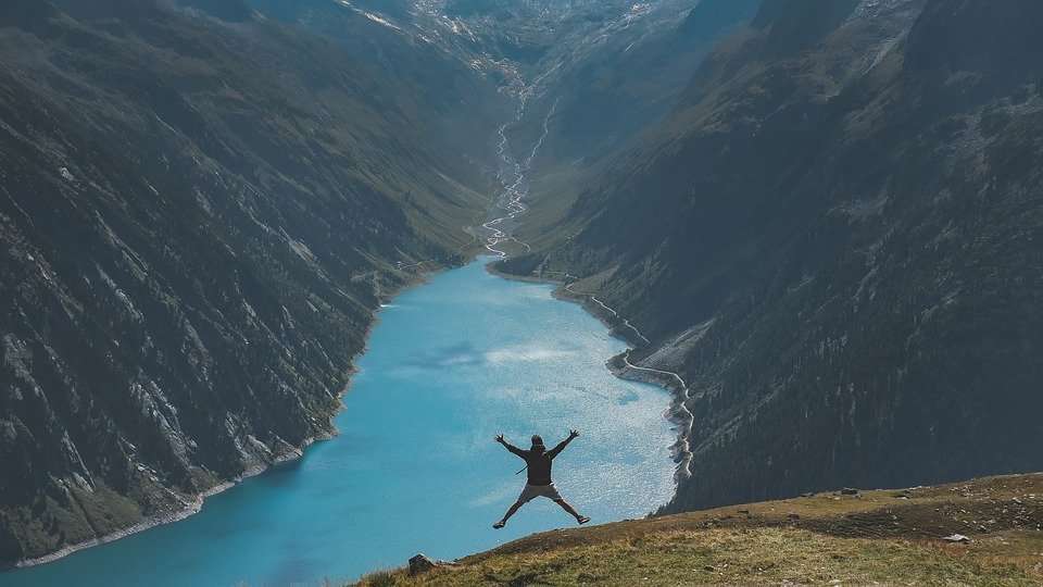 Man jumping of the side of a cliff into the lake