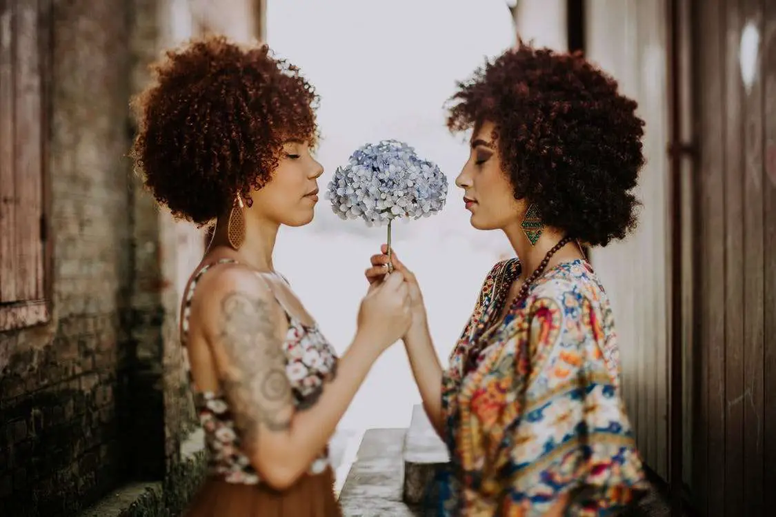 Two Black women smelling the roses with natural hair
