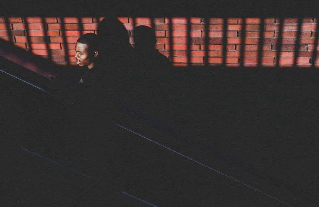 Black Man in New York in front of brick wall coming back from a train