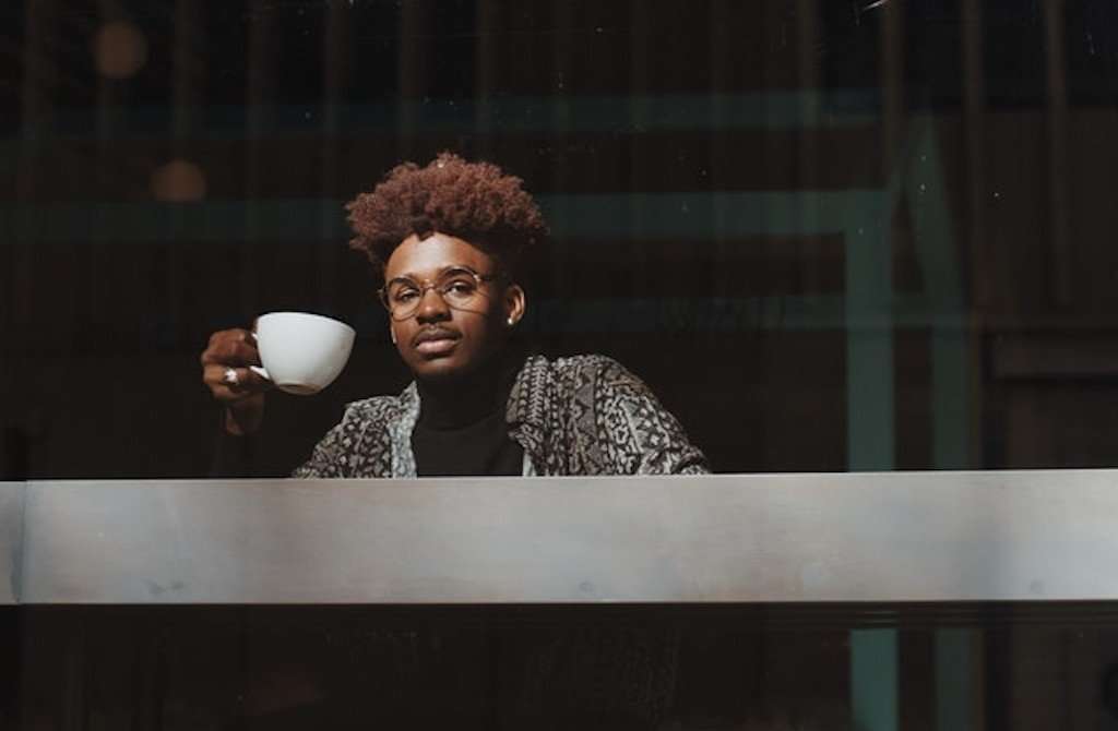 Black Man drinking coffee looking into crowd