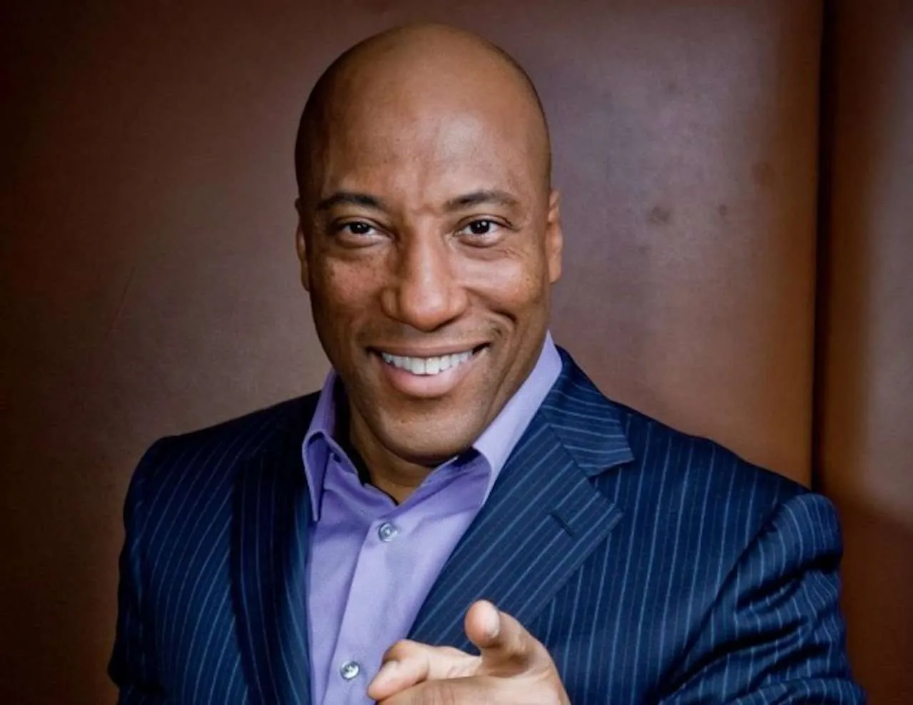 Byron Allen pointing his finger at the camera with a big smile on his face