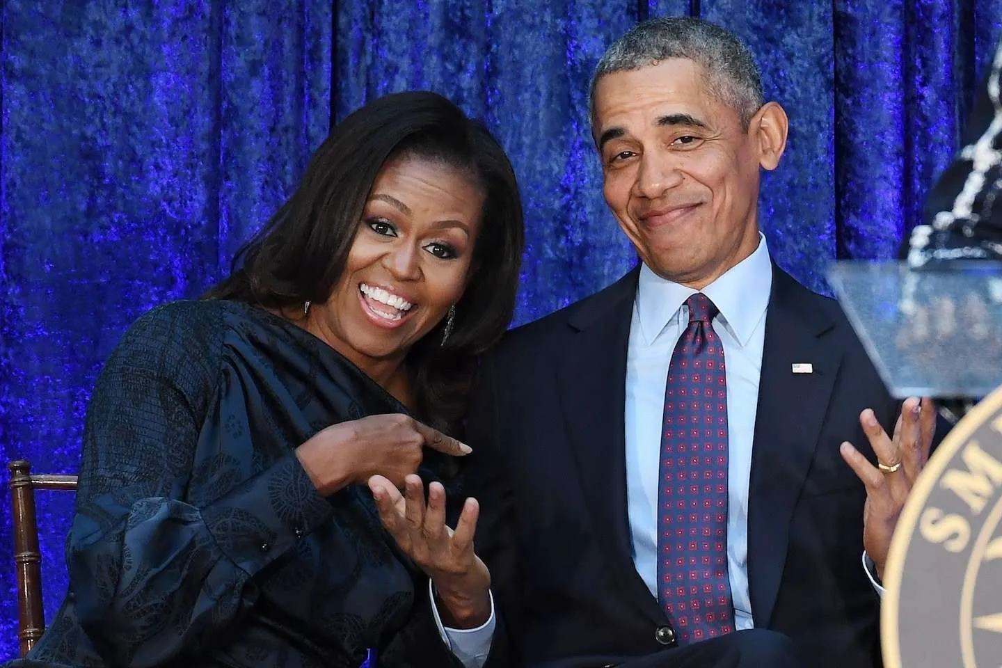 Michelle Obama pointing at Barack Obama laughing happy on stage