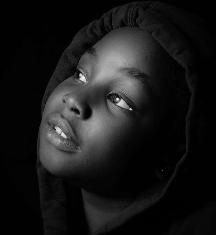 Black child in black and white looking up with hope
