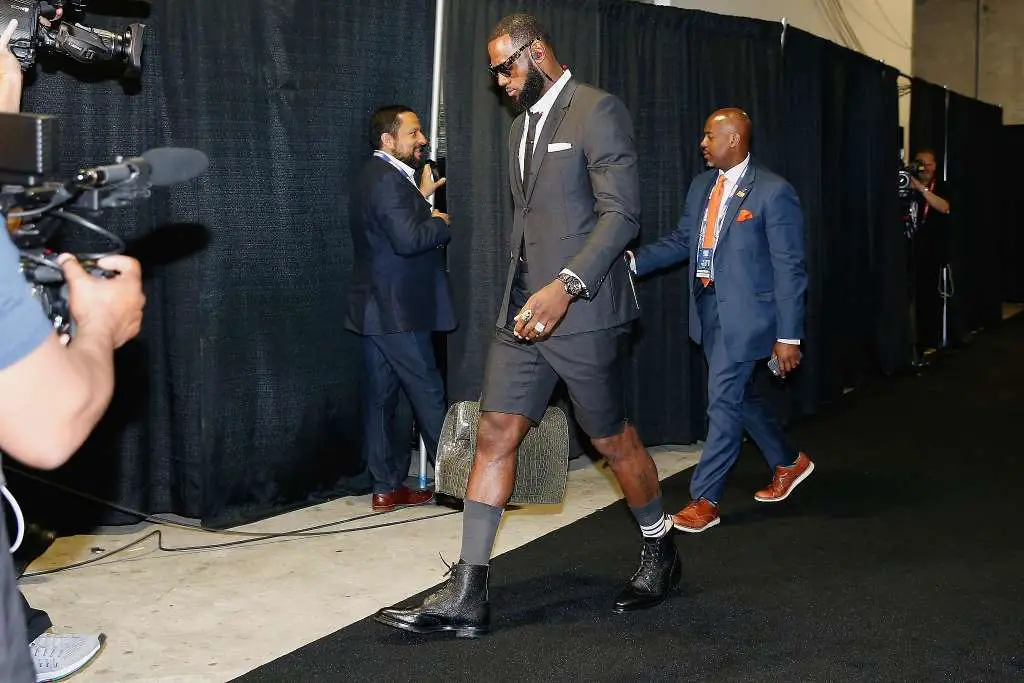 lebron in black suit with boots on and shorts. Also wearing grey high socks and glasses