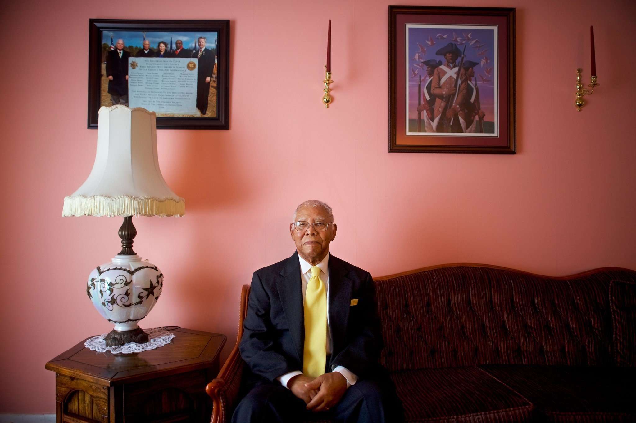 black WWII vet John E. James Jr. sitting at his house in a suit