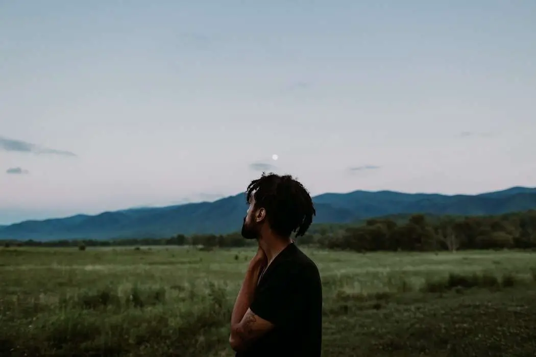 Black man in a empty field looking up at the sky
