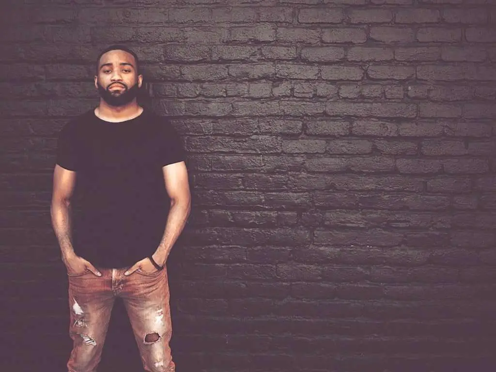 Black Man standing in front of a brick wall