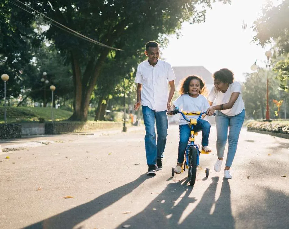 Black Family teaching their child to ride a bike