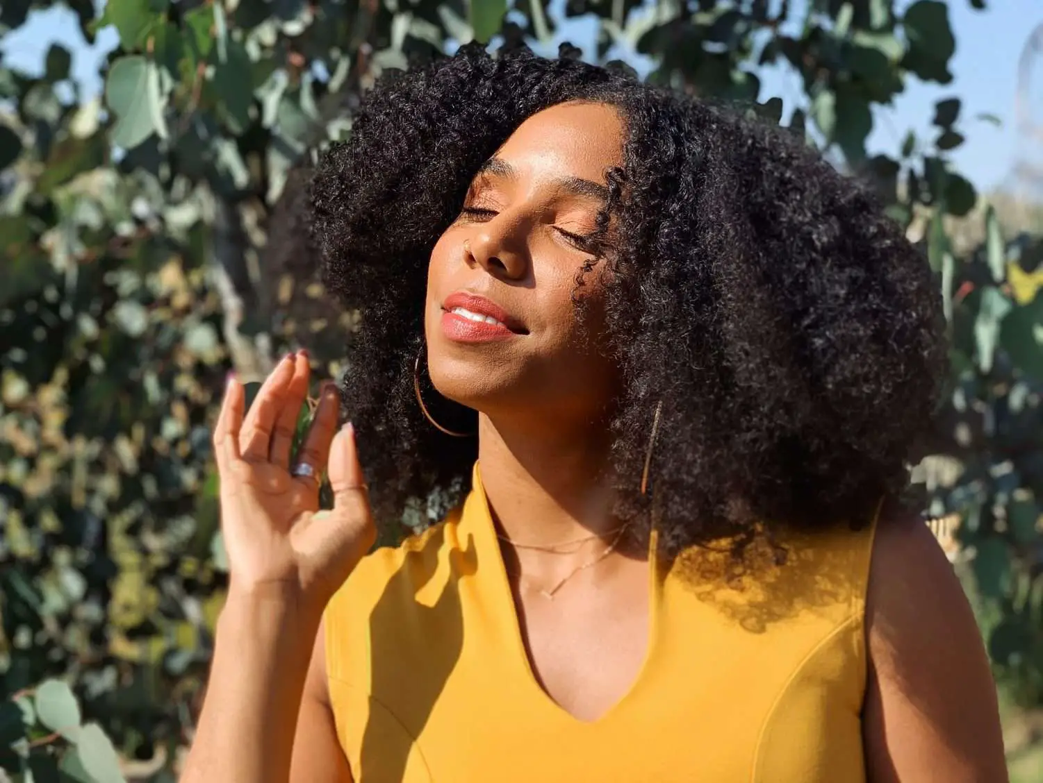 Beautiful Black women taking in the sunshine, wearing yellow with natural hair and eyes closed