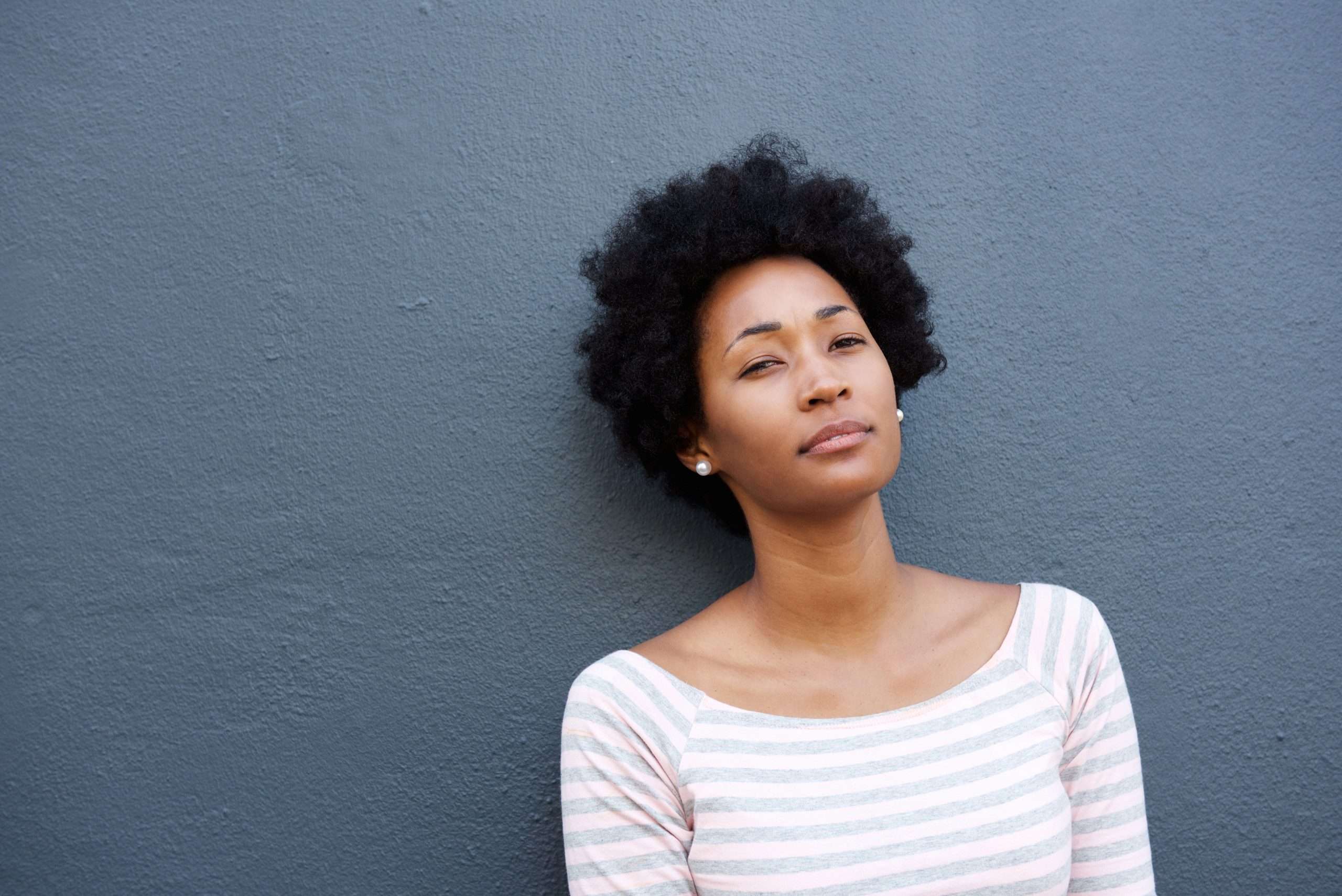 Black Women with natural hair with mental standing against a wall