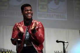 black british star wars actor John Boyega at comic con in San Diego wearing a red jacket 