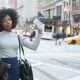 Black business women with natural hair holding up a I phone in the city