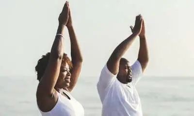 black couple doing yoga at the beach