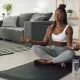 Young African American woman meditating in lotus pose while working out at home.