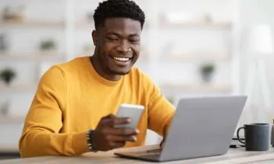 happy black man doing side hustle on laptop