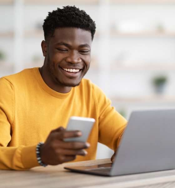 happy black man doing side hustle on laptop